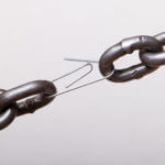 Broken chain link held together by paper clip