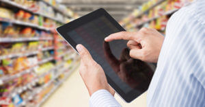 Businessman checking inventory in minimart on touchscreen tablet